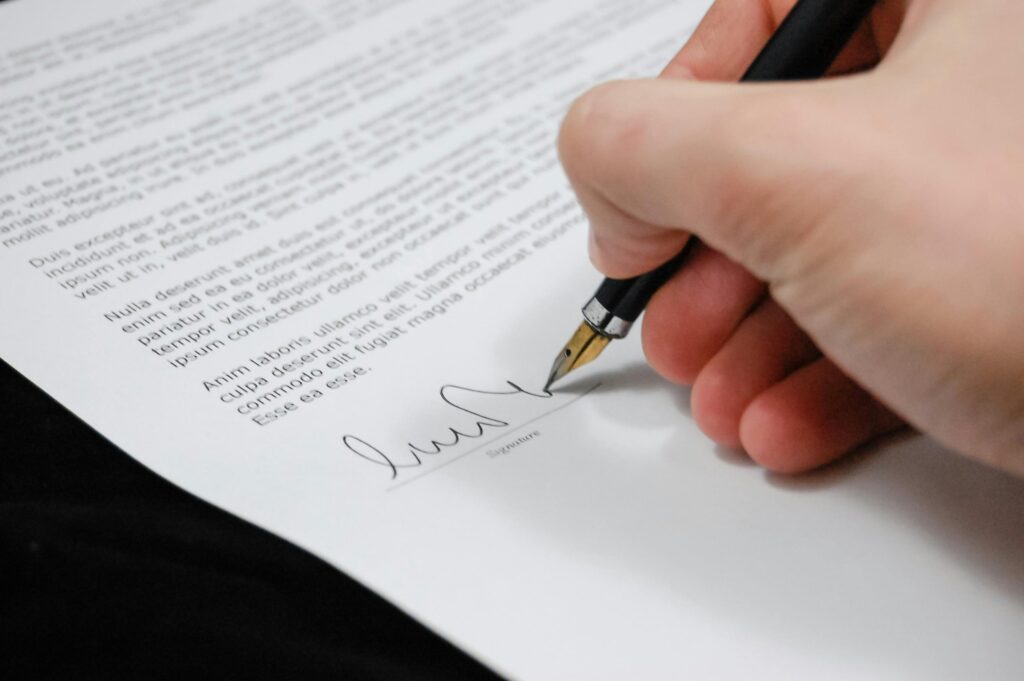 HR Services Close-up of a hand signing a legal document with a fountain pen, symbolizing signature and agreement.